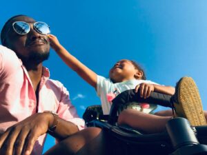 Moment heureux de complicité entre père et fille en plein air sous un ciel bleu clair.